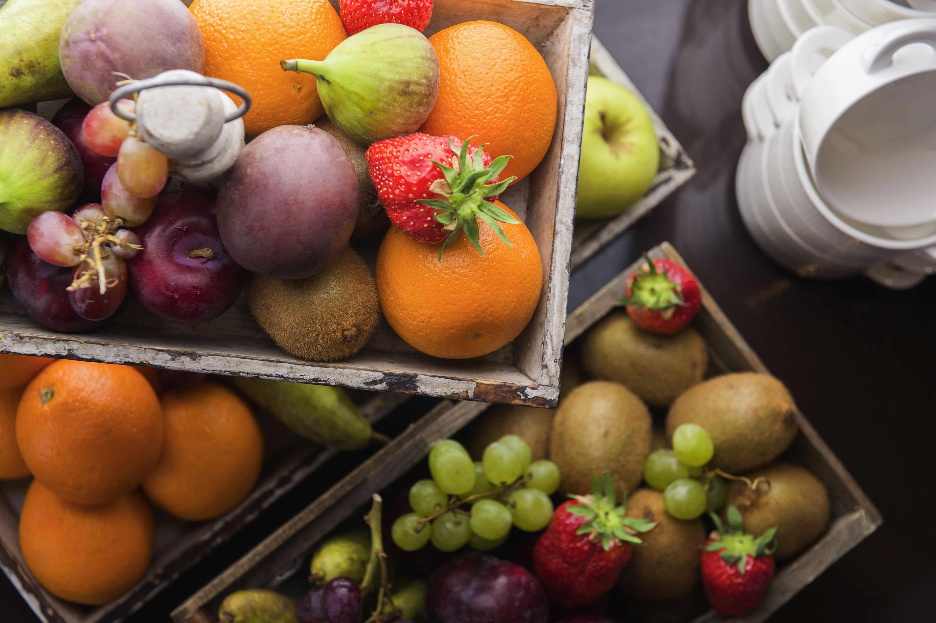 Una caixa de fusta plena de diverses fruites, com ara pomes, taronges i raïms.