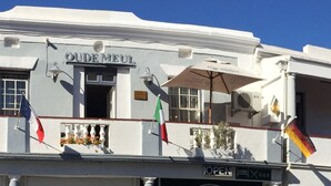 Un edificio con un balcón, banderas y un letrero que dice "OUDE MEUL".