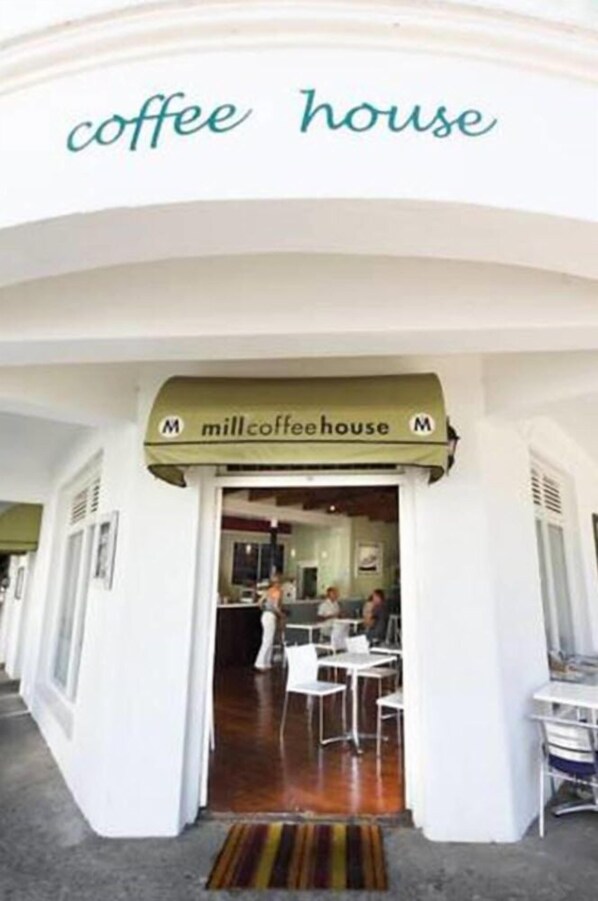 A coffee house entrance with a green awning, white interior, and a few customers inside. - De Oude Meul Guest House (Stellenbosch)