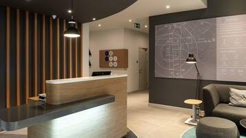 A modern reception desk with a wooden finish, a map on the wall, and a seating area with a lamp.