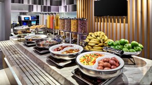 A buffet with various food items, including fruits, vegetables, and hot dishes.