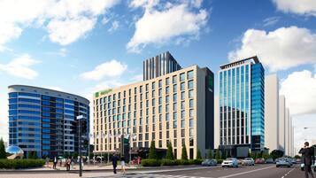A modern hotel with a curved facade, a flat-roofed building with a grid of windows, and a tall building with a reflective glass facade.