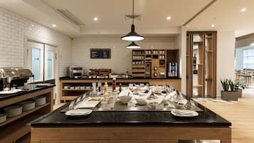 A modern kitchen area with a buffet setup, a coffee machine, and a menu board.