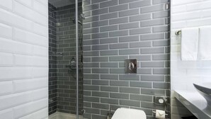 Ein Badezimmer mit Dusche, Toilette und Handtuchhalter.