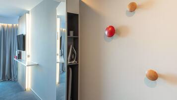 A modern hotel room with a wardrobe, a mirror, and a wall-mounted red and wooden spherical objects.