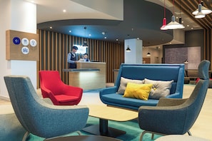 A modern lobby with a reception desk, seating area, and a large informational display.