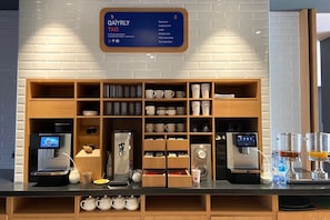 A coffee station with multiple espresso machines, a tea selection, and a variety of mugs and cups. - Holiday Inn Express Astana - Turan (Astana)