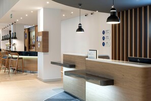 A modern reception desk with a wooden finish, a black pendant light, and a sign indicating a gift shop.