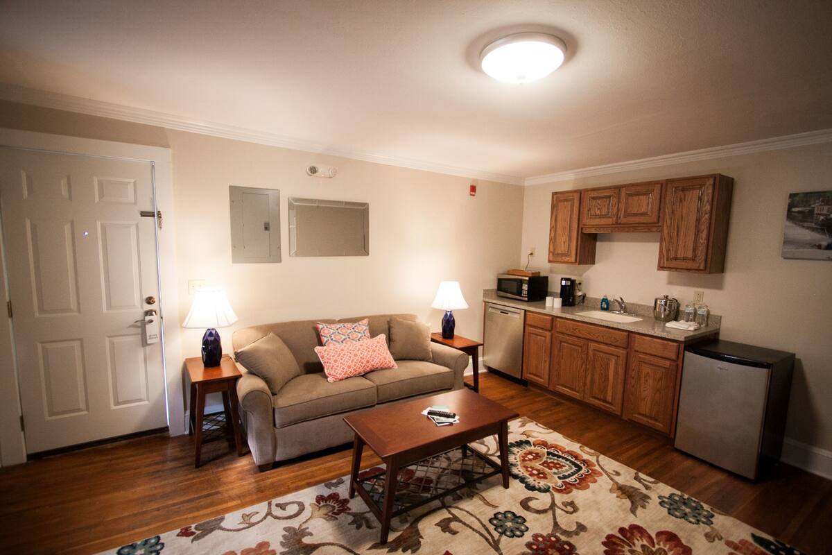 Un espacio habitable pequeño con sofá, mesa de centro y una zona de kitchenette.