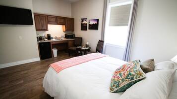 Une chambre d’hôtel comprenant un lit, un bureau avec une chaise, un four à micro-ondes et un petit coin cuisine.