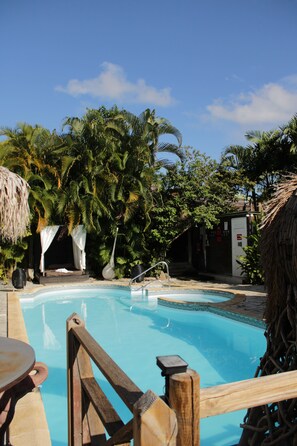 Una piscina al aire libre, sombrillas, sillones reclinables de piscina