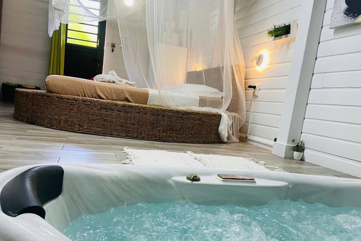 A cozy bedroom with a bed, a small hot tub, and a canopy bed.