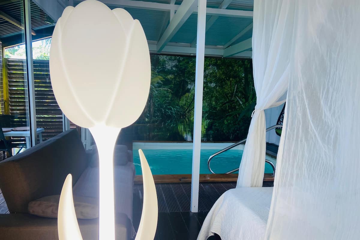 A modern room with a large window, a pool view, and a white flower decoration.