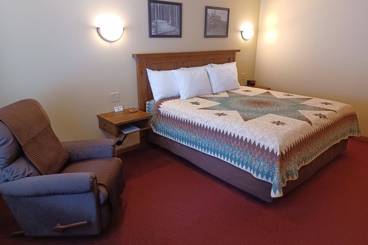 A neatly arranged bedroom with a bed, a chair, and two wall-mounted lamps.