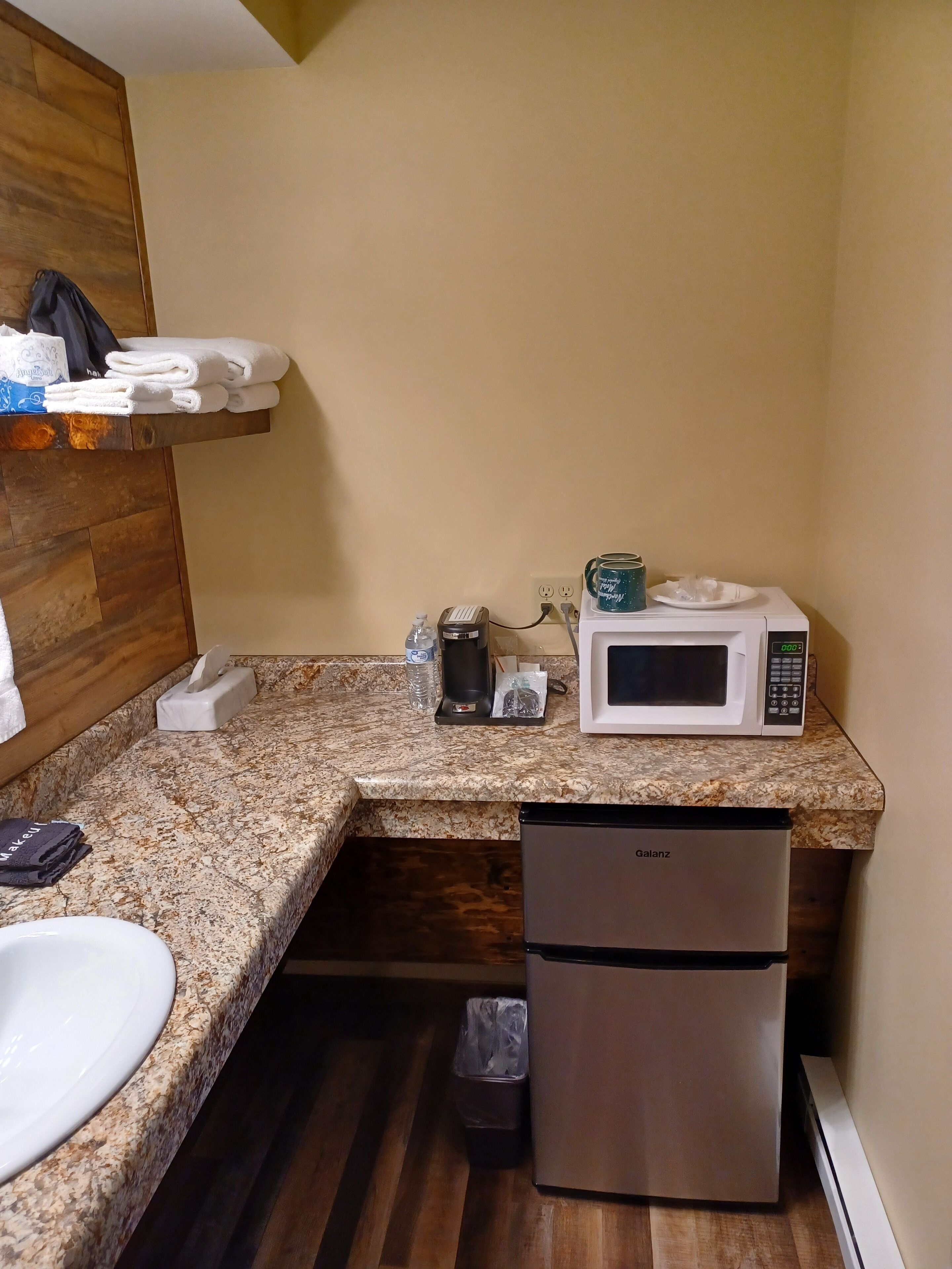 A compact kitchen with a microwave, coffee maker, and a refrigerator.