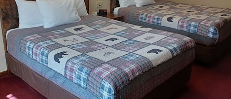 Camera d'albergo con due letti, ciascuno con copriletto trapuntato con stampe animalier. Sono presenti luci a parete e due quadri sopra i letti.