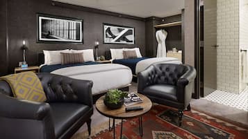 Une chambre d’hôtel moderne avec deux lits, un canapé en cuir, une table basse et un tapis à motifs.