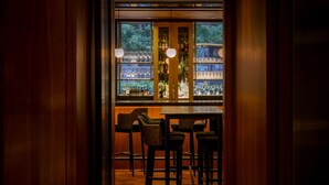 A bar area with wooden paneling, bar stools, and shelves stocked with bottles and glasses. - The Anndore House, part of JdV by Hyatt (Toronto)