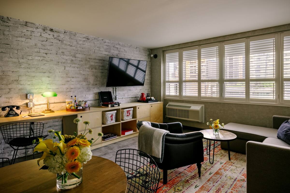 Un salon moderne avec un mur en briques, un téléviseur à écran plat, une table à manger en bois et un canapé.