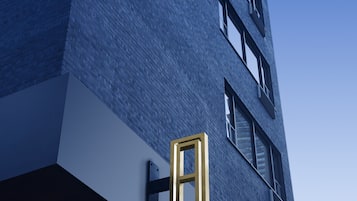 Um edifício alto com fachada de tijolos azuis e uma janela com moldura dourada marcante.