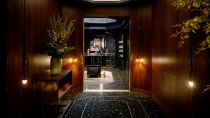 A hallway with wooden walls, a marble floor, and a central island with a sink. - The Anndore House, part of JdV by Hyatt (Toronto)
