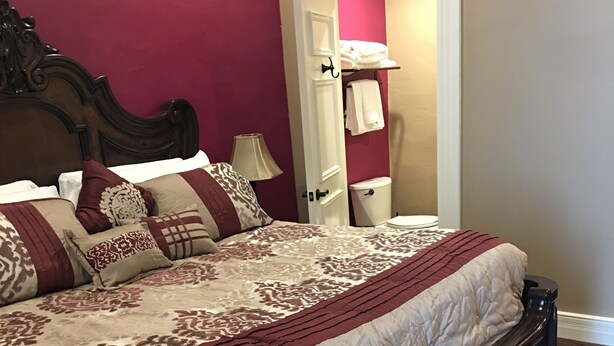 Ein Schlafzimmer mit einem hölzernen Bett, einem Nachttisch, einer Lampe und einer Tür zu einem Badezimmer.