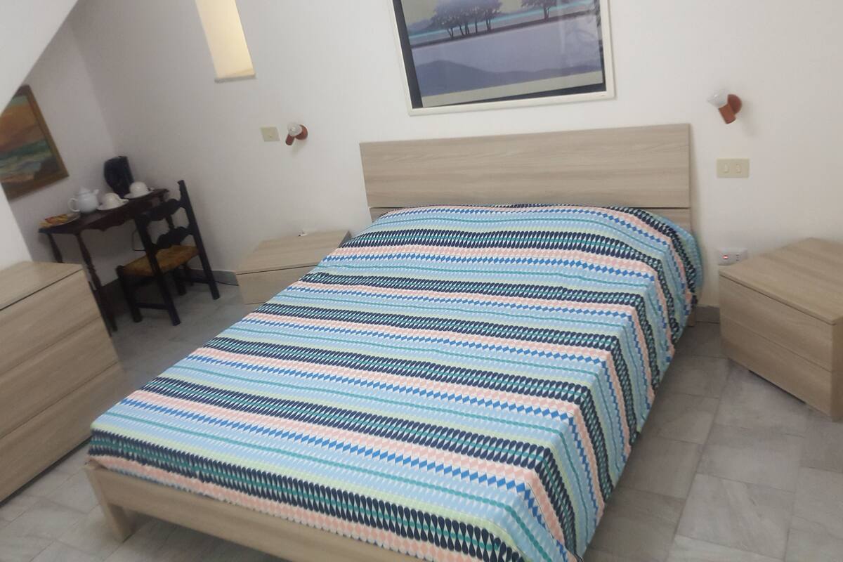 A bedroom with a bed, bedside tables, a desk, and a chair.