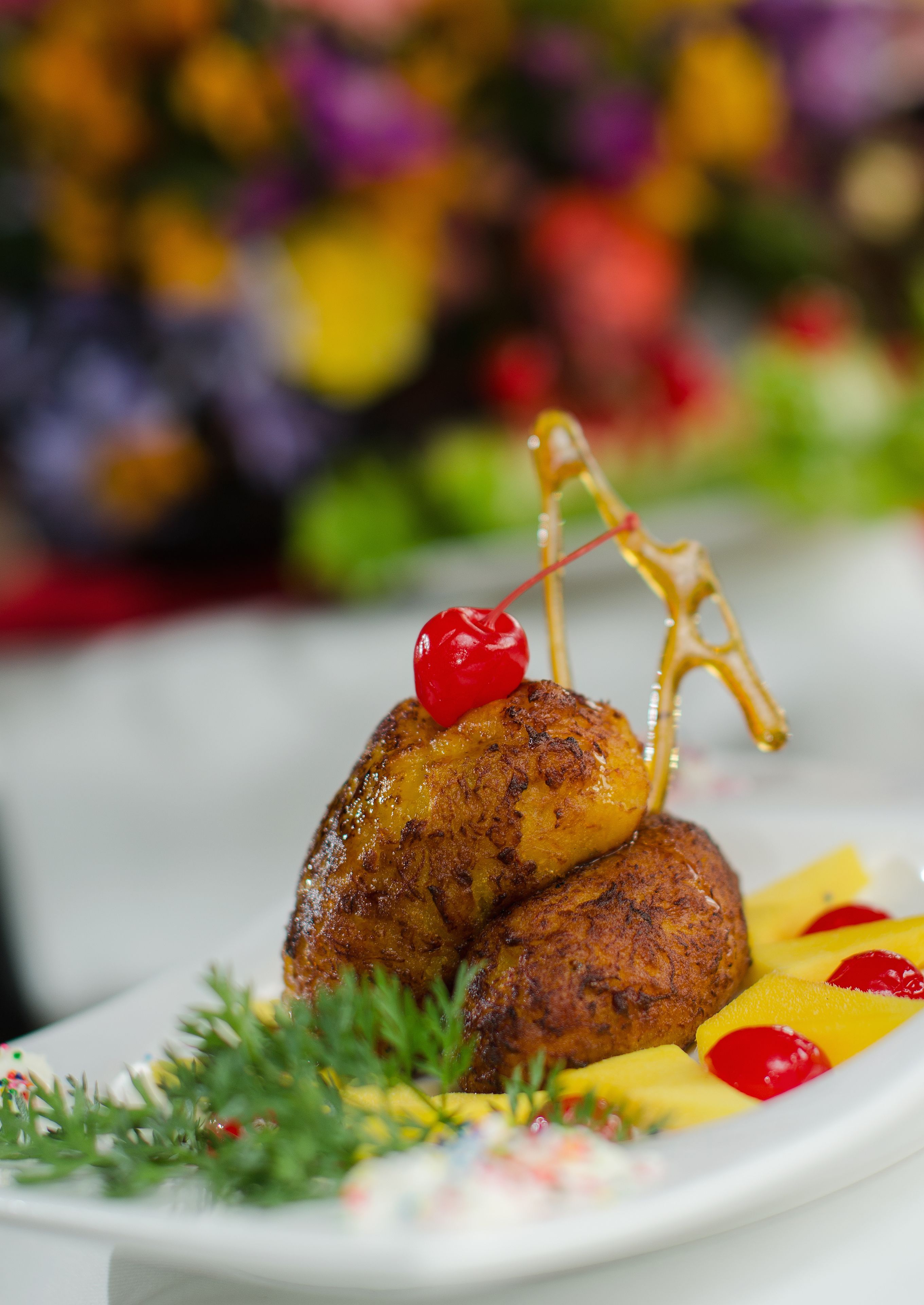 Un plato con un guiso de carne glaseado, adornado con una cereza y un detalle de metal decorativo.