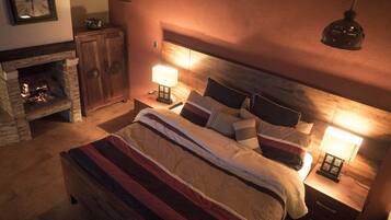 Un dormitorio acogedor con chimenea, una cama grande con ropa de cama a rayas y dos lámparas de noche.