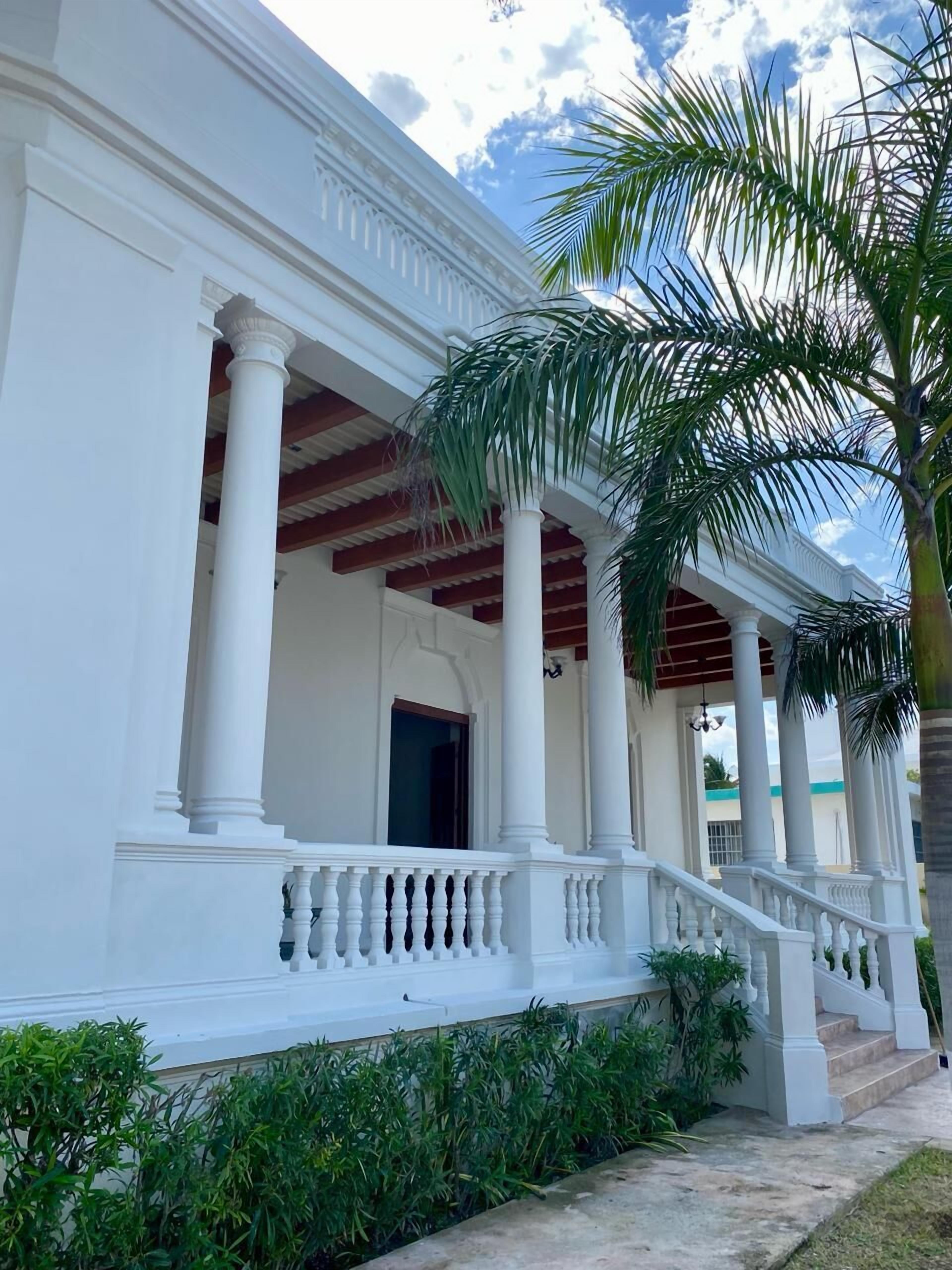Un edificio blanco con columnas y un balcón.