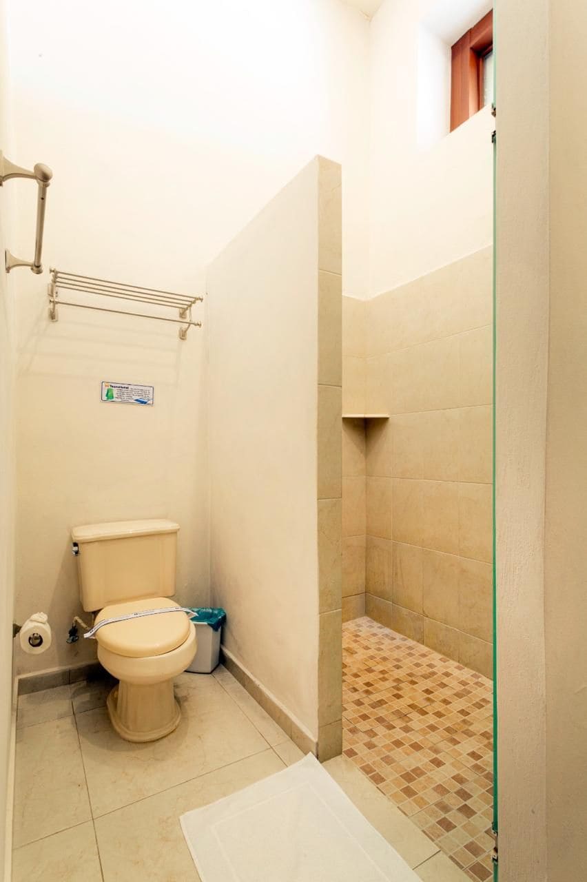 A small bathroom with a toilet, a shower area, and a tiled floor.