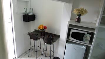Cozinha compacta com área de refeições, micro-ondas e pequena geladeira.