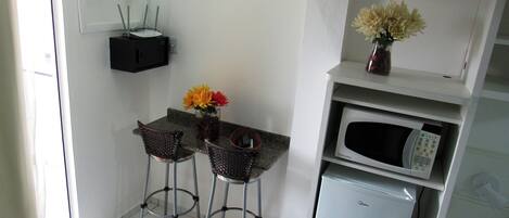 Una cocina compacta con comedor, microondas y un refrigerador pequeño.