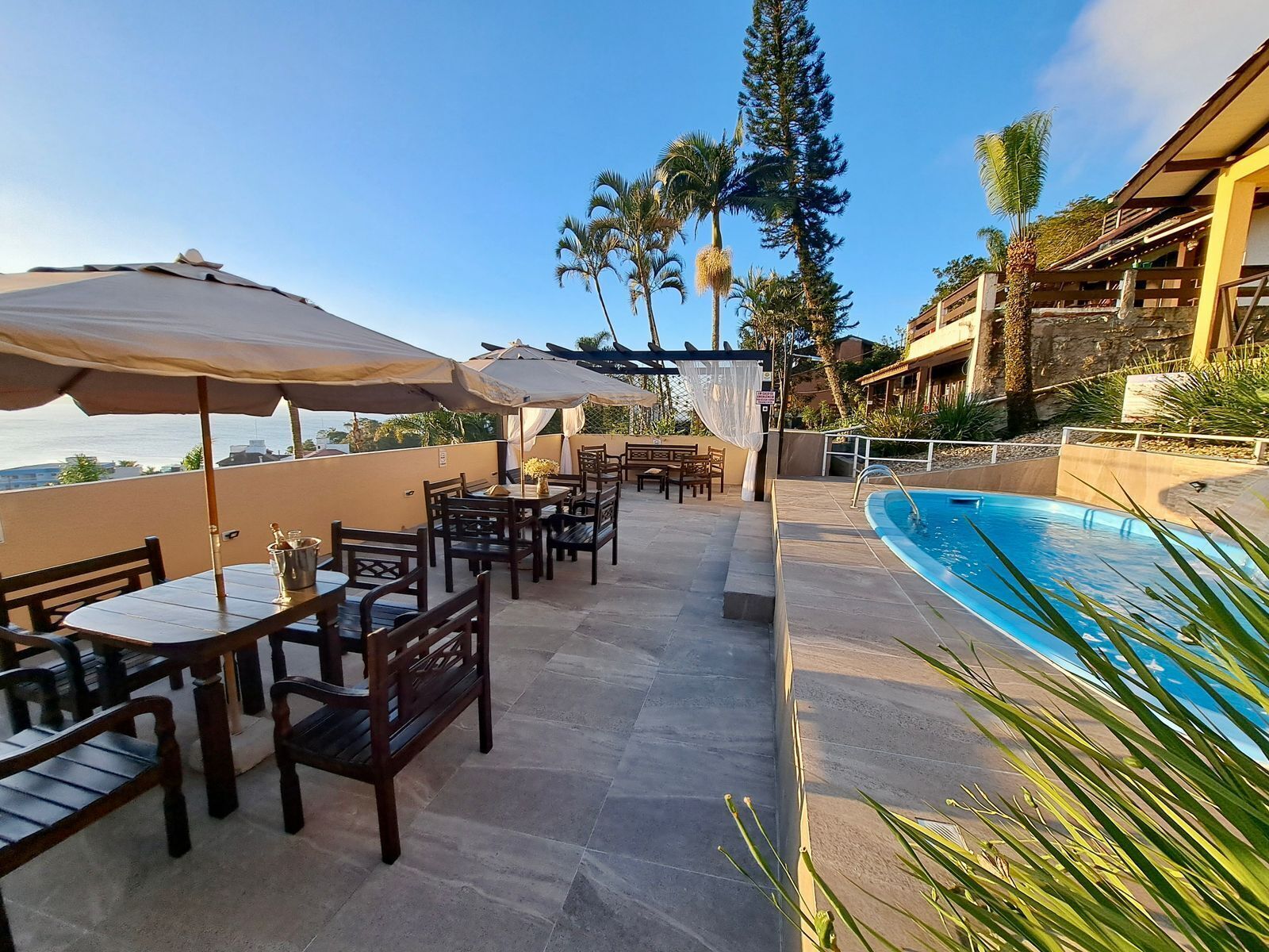 Uma área de piscina no terraço com mobiliário de exterior e vista para o oceano.