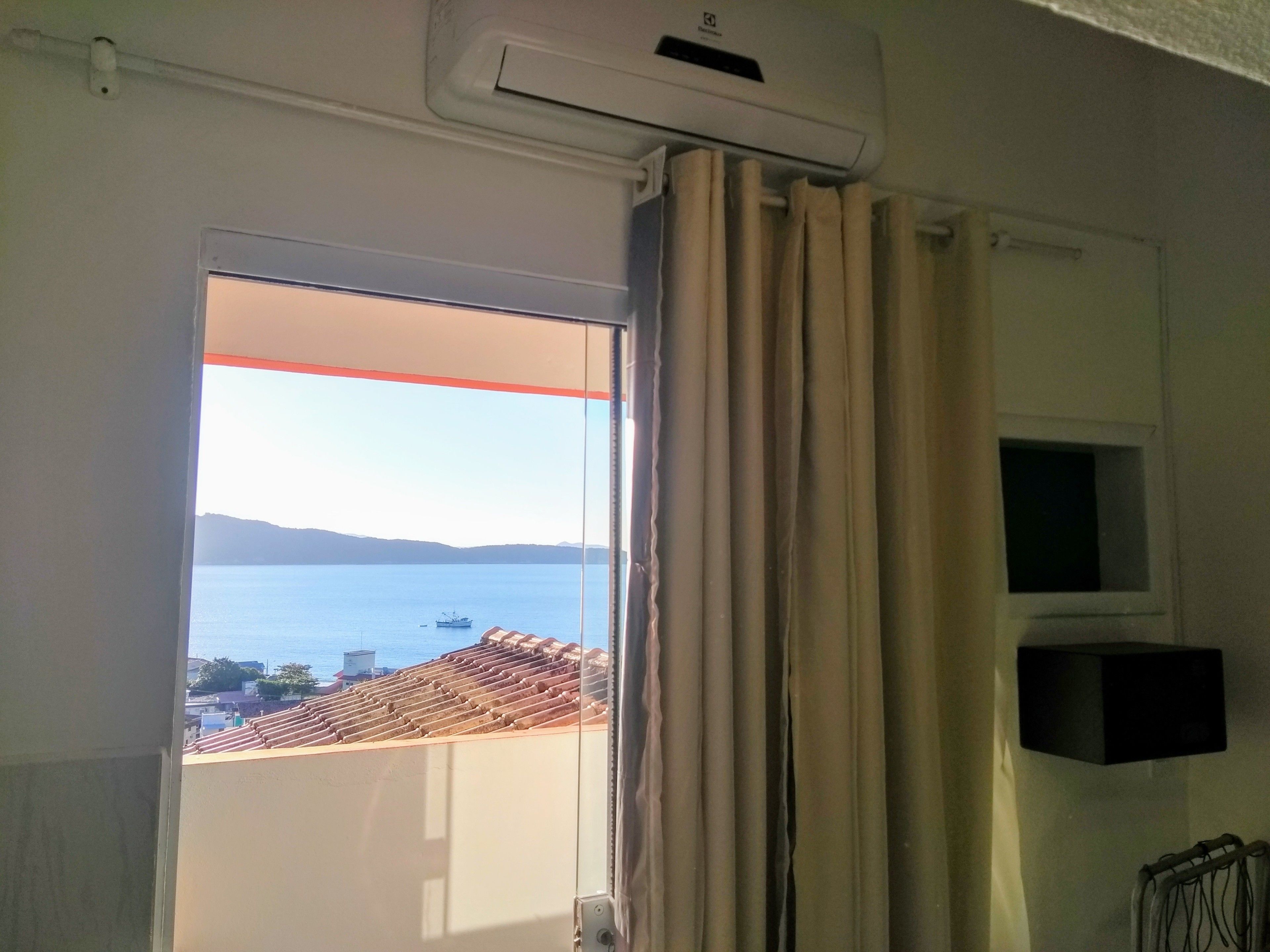 Una habitación con un ventanal grande, aire acondicionado instalado en el techo y vistas a un paisaje costero.