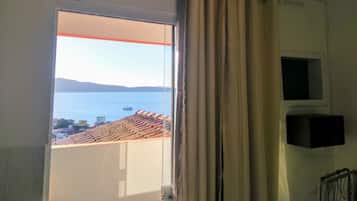 Una habitación con un ventanal grande, aire acondicionado instalado en el techo y vistas a un paisaje costero.