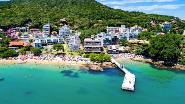 Un pueblo costero con playa, muelle y edificios modernos.