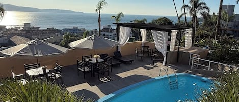 A poolside area with lounge chairs, umbrellas, and a view of the ocean.