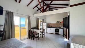 Una habitación compacta con kitchenette, zona de comedor y cama.