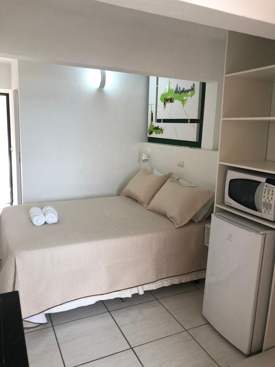 Een kleine, praktische kamer met een bed, een magnetron en een koelkast.