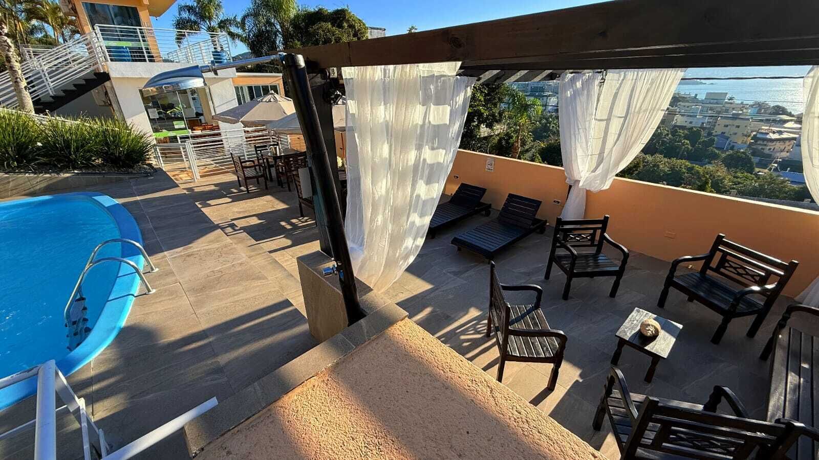 A rooftop pool area with a view of the city, outdoor seating, and a staircase leading to an upper level.