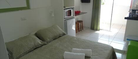Ein Hotelzimmer mit Bett, Küchenzeile, einer kleinen Essecke und Blick durch eine Glastür.