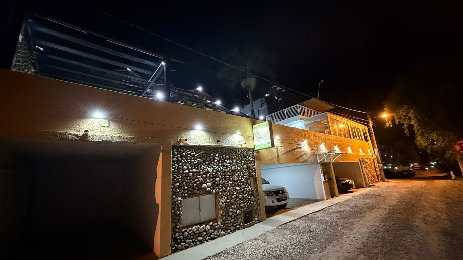 Un edificio de fachada de piedra, con garaje y una entrada bien iluminada de noche.