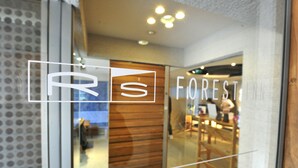 A modern interior with a glass door, wooden paneling, and a seating area visible through the glass.