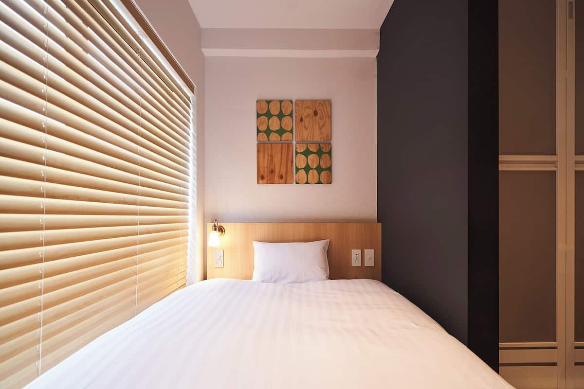 Quarto de hotel com uma cama grande, cabeceira de madeira e uma obra de arte pendurada na parede.