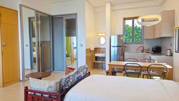 Une chambre d’hôtel comprenant un lit, une petite table, des chaises, un coin cuisine et une porte coulissante donnant sur une autre pièce.