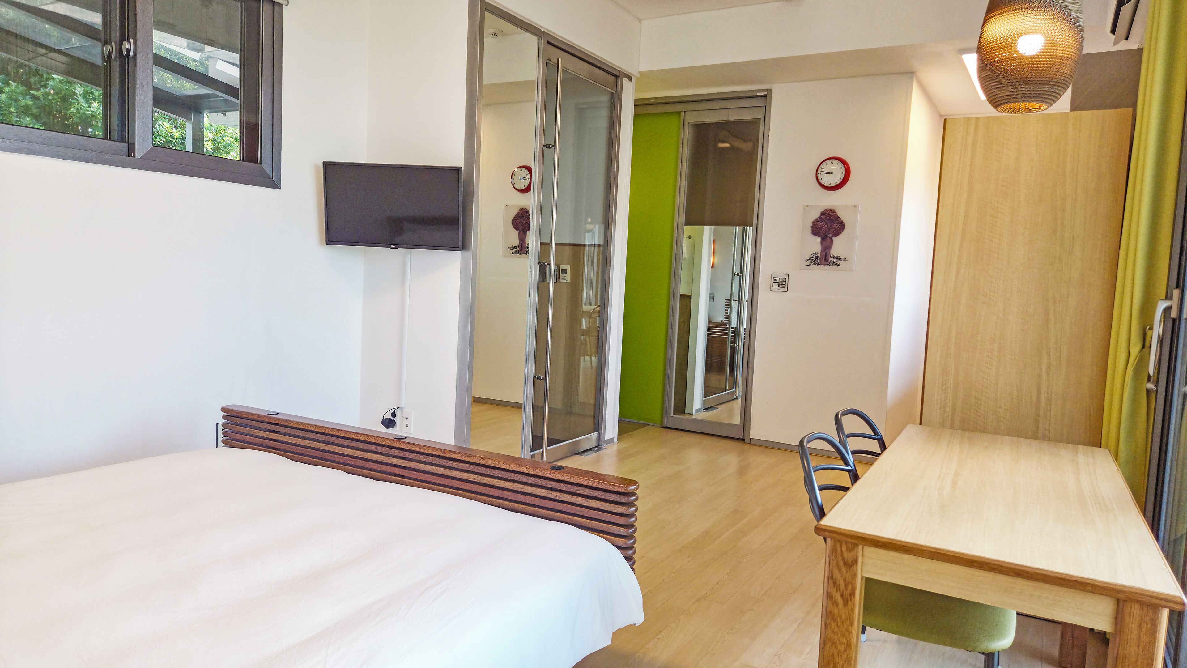 A hotel room with a bed, a desk, a chair, a television, and a door leading to a bathroom.