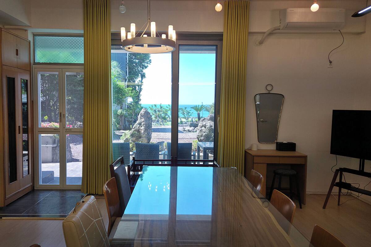 A dining area with a large table, chairs, a television, and a view of the outdoors.