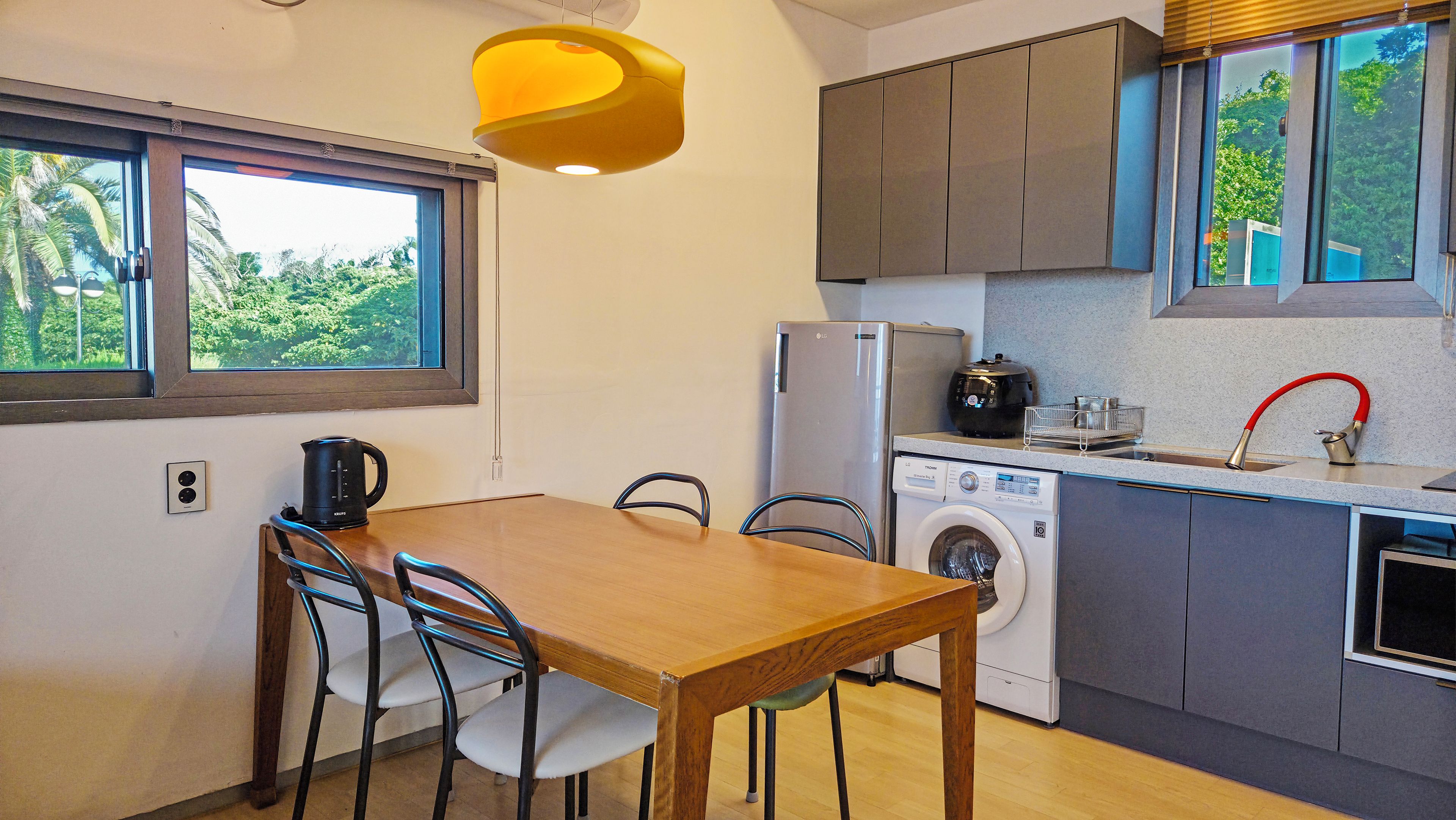 A compact kitchen with a washing machine, a kettle, and a built-in oven.