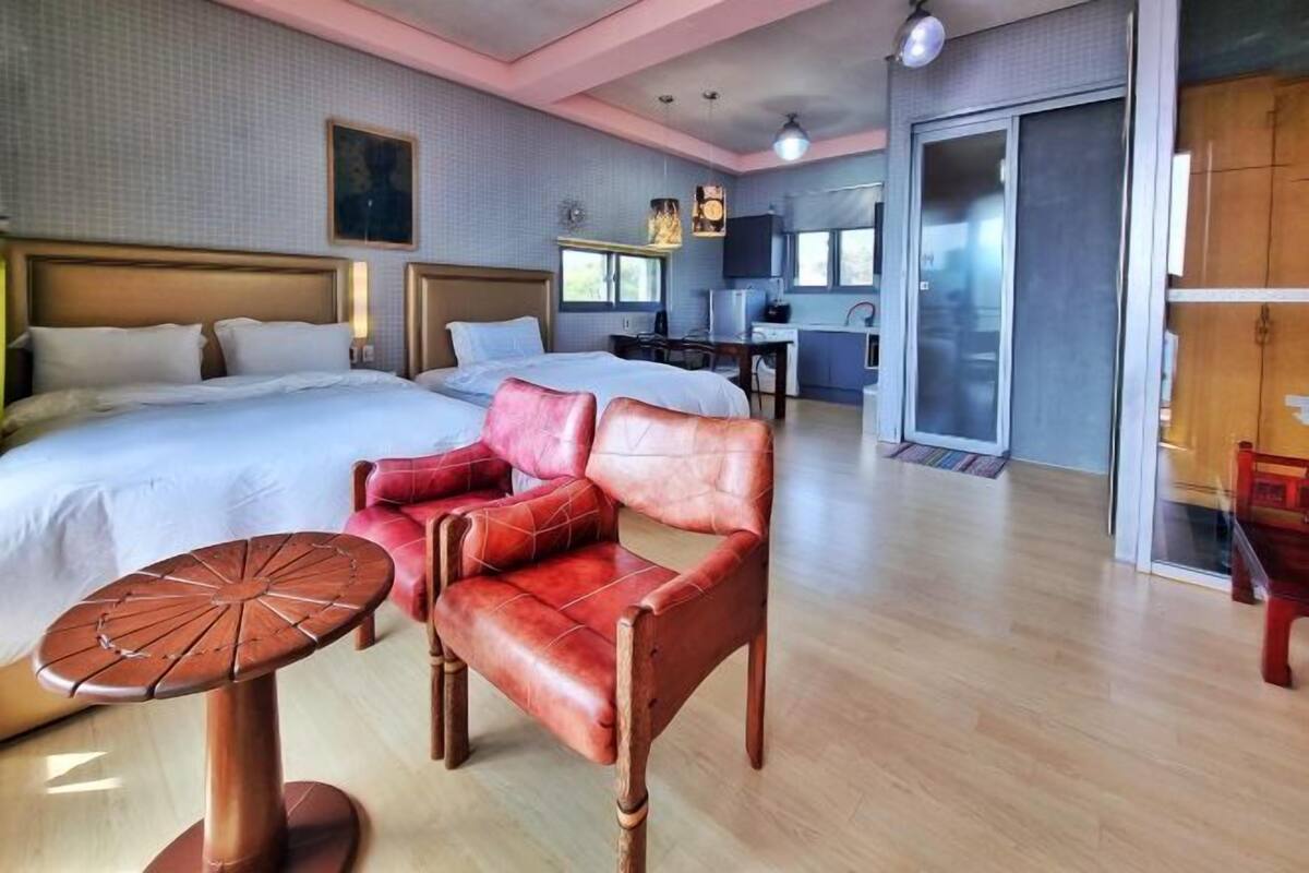 A hotel room with a large bed, a desk, a chair, and a small table.